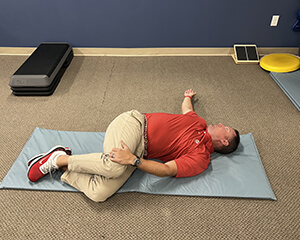 Man lying on his side with knees bent for a stretch.