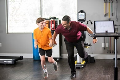 Male therapist doing one-leg balance exercises with a young therapy patient