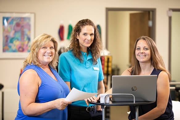 Three professional woman gathered at a nurses station