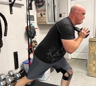 Bert is wearing his knee brace while exercising with a kettle bell
